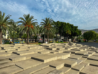 Fototapeta premium Artistic monument made of stone steps in the park and promenade at the harbor in Funchal, Madeira island, Portugal, Europe. Steps made of concrete and there are palm trees on either side of the square