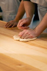 layout in a professional kitchen a group of bakers at the table process the dough and form it into...