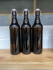 3 flagon bottle in a row, swing top brown bottles for beer or ale grey brick background