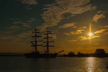 The sailing ship comes to the port of sunset, silhouette