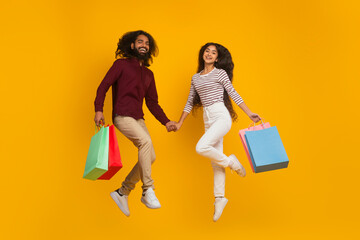 Emotional young indian couple jumping with shopping bags