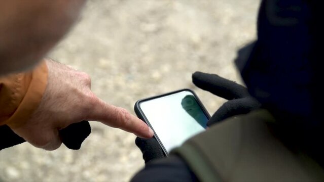 Slow motion, hikers checking a digital map on the phone, outdoors