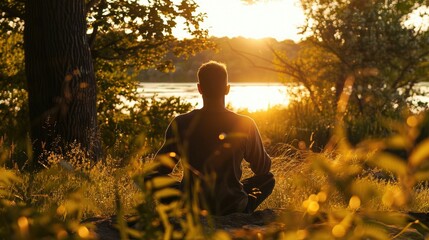 Silhouetted person meditating peacefully on a rock by a calm lake at sunrise, surrounded by nature.
 - obrazy, fototapety, plakaty