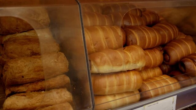Self-service display with sausage rolls in supermarket. Counter full of delicious buns and pastries in a shop bakery.