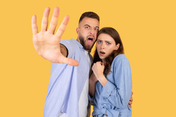 Frightened young european couple gesturing stop to camera