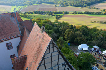 View from above of the roof of an old castle,  landscape and tents in the forecourt - obrazy, fototapety, plakaty