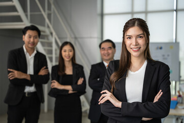 Portrait of a confident businesswoman with her team in the background at a bright contemporary office space.