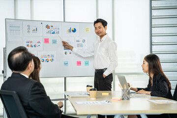 Man presenting statistical data to attentive colleagues during a business strategy meeting in a modern office setting.