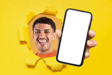 Laughing man in an orange shirt breaking through a yellow torn paper wall