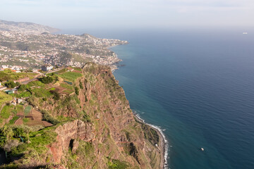 Fototapeta na wymiar Spectacular aerial view of city Funchal seen from viewing platform Cabo Girao Skywalk, Madeira island, Portugal, Europe. Majestic coastline with steep cliffs along Atlantic Ocean. Travel destination