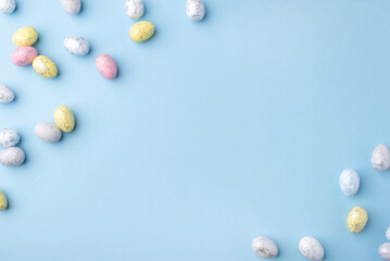 Festive Easter background. Multicoloured Easter eggs on a blue table. Card with a place for text. Top view.