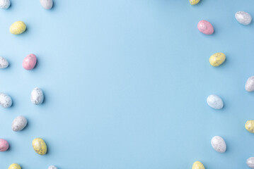 Festive Easter background. Multicoloured Easter eggs on a blue table. Card with a place for text. Top view.