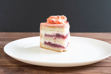 close-up of a piece of delicious layer cake on a white plate. Wooden table, dark background