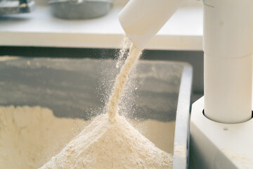 outline of the process of pouring flour through a tube into an iron container in professional...
