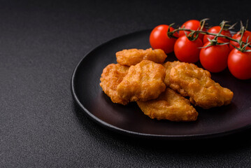 Delicious fresh crispy chicken nuggets on a dark concrete background