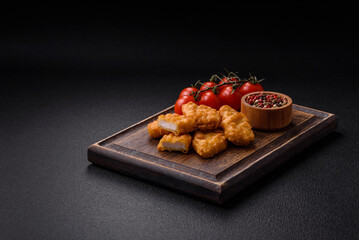 Delicious fresh crispy chicken nuggets on a dark concrete background