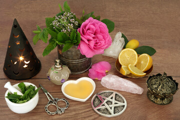Wiccan love potion preparation for magic spell with ingredients of rose flower, quartz crystals, thyme, mint, lemon fruit, honey and witches hat candle. Romantic magical concoction.