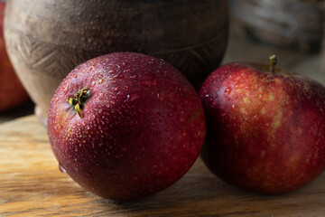 Fototapeta na wymiar Wet red apples near a ceramic pot on a wooden table
