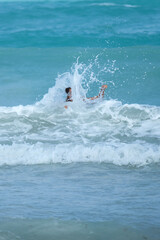 A wave hitting a woman in the face in a turquoise sea