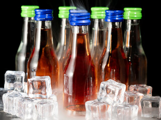 Small bottles of alcoholic drinks in ice cubes. Bottles with alcohol close-up.