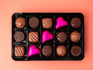 Box of chocolates on a pink background. Chocolate candies close-up.