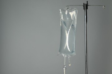 IV infusion set on pole against grey background. Space for text