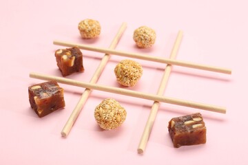 Tic tac toe game made with sweets on pink background, closeup