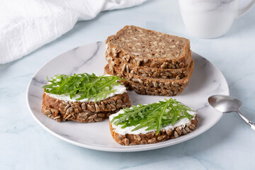 Sandwiches with curd cheese and arugula. Rye bread with seeds