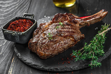 Tomahawk rib beef steak with spices and herbs on a dark background. top view. copy space for text