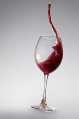 Glass of red wine with splashes on white