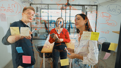 Creative start up team brainstorming marketing idea while cooperative caucasian businessman presents creative solution in front of glass board at business meeting. Working together. Immaculate.