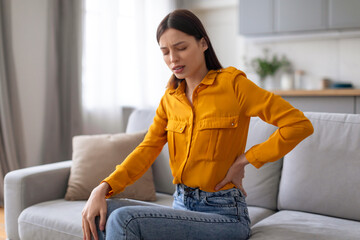Young woman with back pain on couch