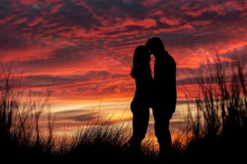 Tuinposter A man and a woman sharing a passionate kiss as the sun sets in the background, casting a warm glow over the scenic coastal landscape © Konstiantyn Zapylaie