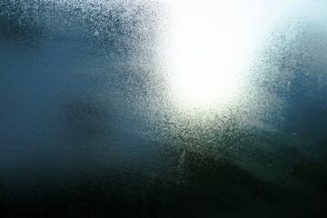 Abstraktes Motiv mit beschlagener gefrorener Glasscheibe vor blaugrauem Himmel mit weißem...