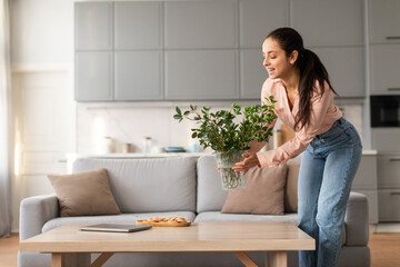 Woman admiring green plant on coffee table in cozy room