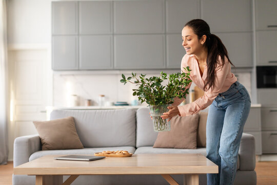 Woman Admiring Green Plant On Coffee Table In Cozy Room