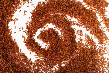 Brown rice is scattered in a circle on a white background. Background with a pattern of brown rice
