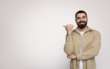 Cheerful bearded man giving a thumbs-up sign, confidently smiling in a casual beige shirt