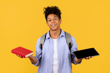 Student guy balancing book and tablet, choosing between traditional and digital learning