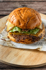 Deliciosa hamburguesa con doble carne aplastada, doble queso sobre tabla de cocina en una mesa de...