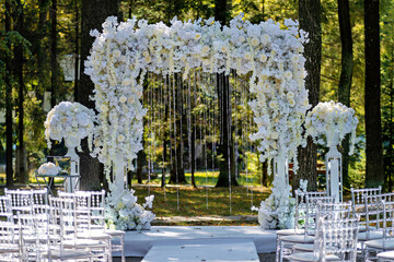 Wedding ceremony setup with white flowers and white draping on the aisle