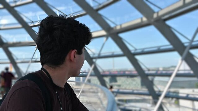 Berlin, Germany, August 15, 2023. Footage inside the glass and metal dome located on the roof of the Reichstag building. A young man looks around, blurred background, beautiful summer day.