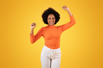 Radiant young woman with afro hair joyously raises her arms in a celebratory gesture