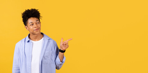 Confident black guy pointing sideways on yellow background