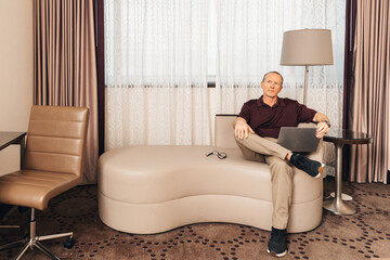 man in casual business attire working on a laptop in a hotel room