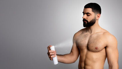 Handsome bearded middle eastern young man spraying deodorant