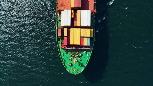 Aerial top down view of a bow of large container cargo ship cruising with speed in sea
