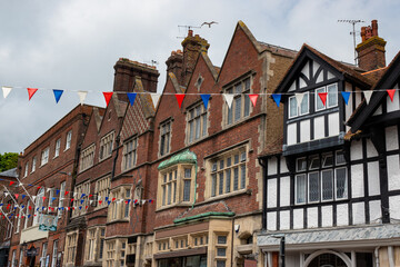Naklejka premium Cloudy skies over classic Tudor architecture and festive bunting in English town
