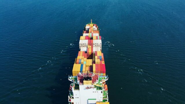 Intermodal container cargo vessel cruising in sea near commercial port. Aerial view
