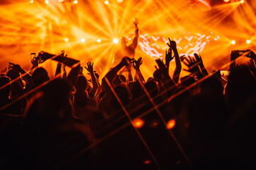 Silhouettes rising their hands on an open air music festival concert